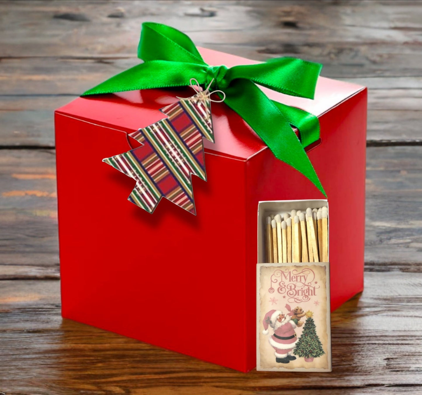 Red gift box with green ribbon and Christmas-themed matches on a wooden surface @ CarolinaCart.com
